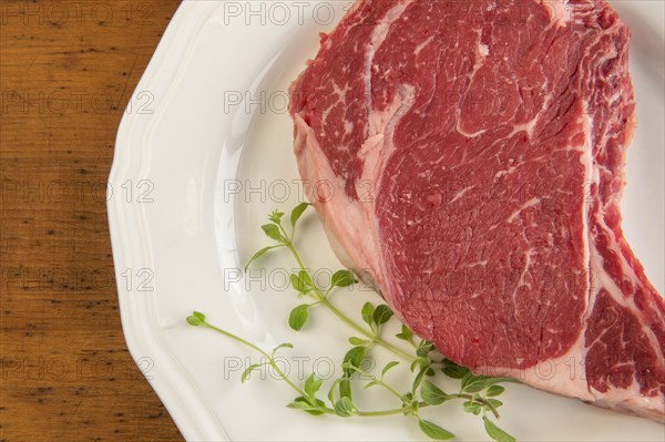 Raw steak and oregano on plate