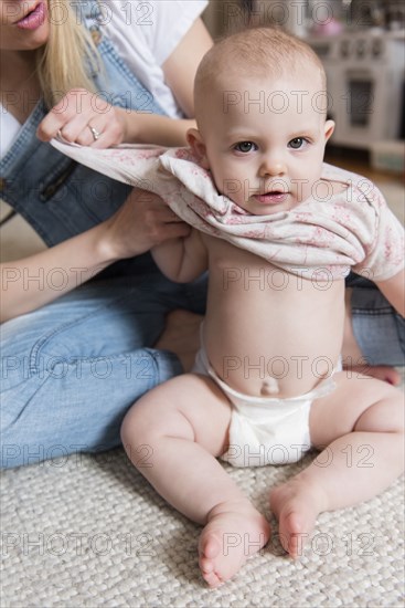 Baby girl being dressed by her mother