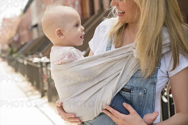 Mother carrying her daughter in baby carrier