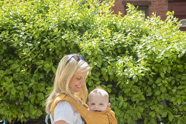 Mother carrying her daughter in baby carrier