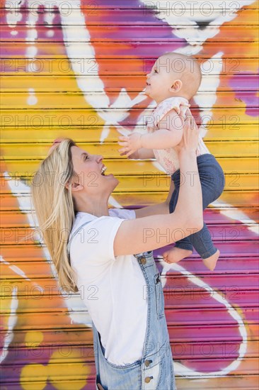 Smiling mother lifting her baby daughter