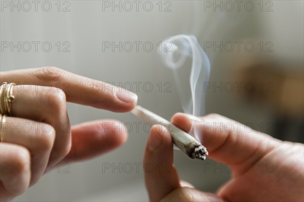 Hands of man and woman passing marijuana joint