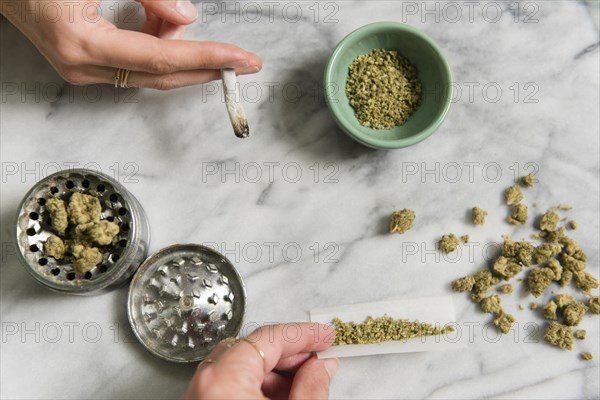 Hands of women rolling and smoking marijuana joints