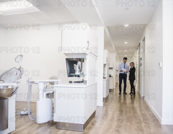 Dentist and dental nurse discussing notes in corridor