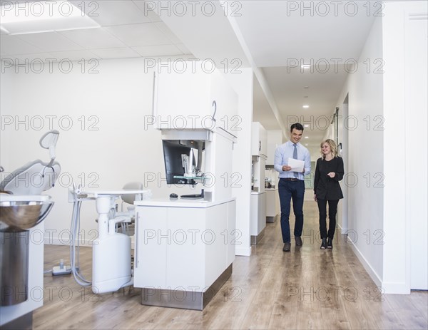 Dentist and dental nurse discussing notes in corridor