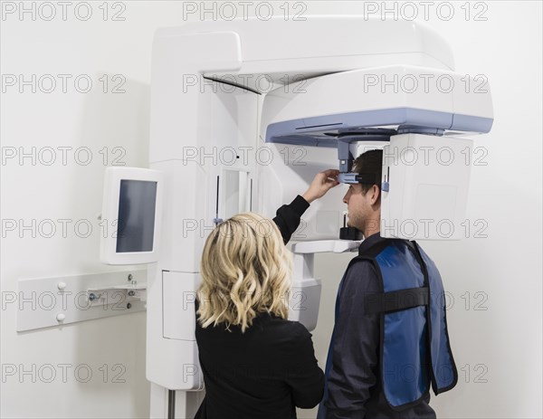 Dental nurse adjusting x-ray machine for patient