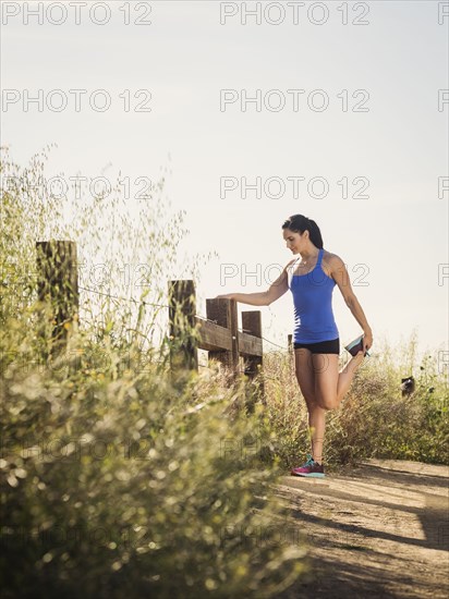 Woman in sportswear stretching on fence