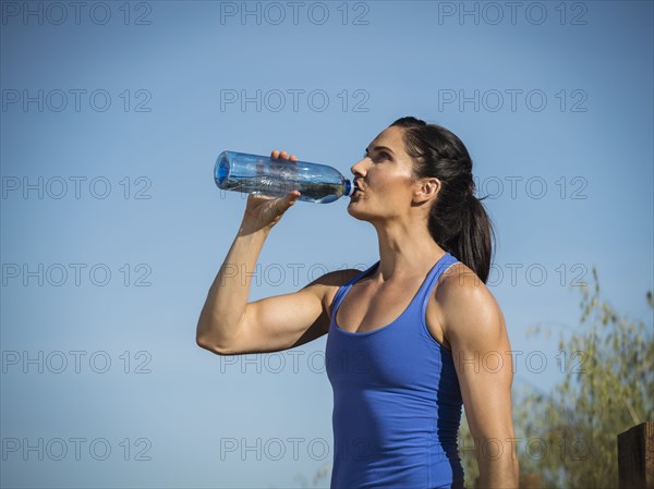 Woman in sportswear drinking from water bottle