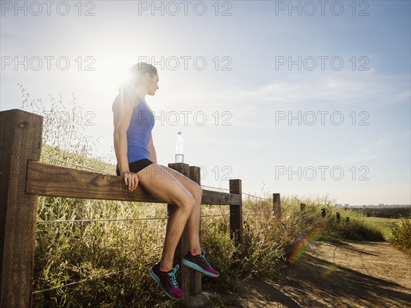 Woman in sportswear sitting on fence