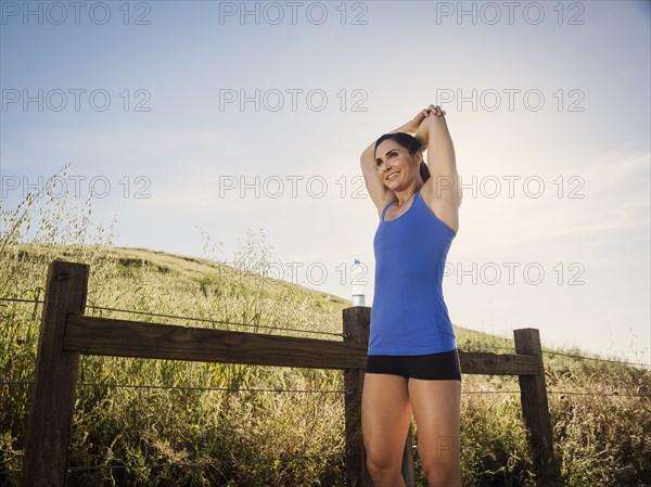 Woman in sportswear stretching by fence