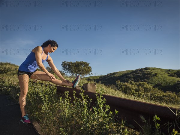 Woman in sportswear stretching on fence