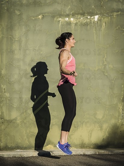 Woman skipping by concrete wall