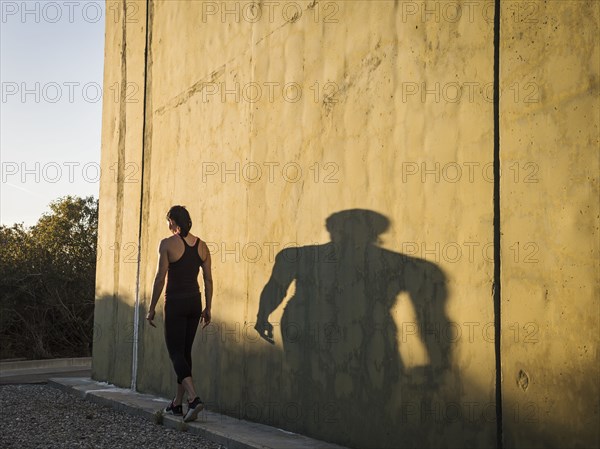 Woman in sportswear walking by concrete wall