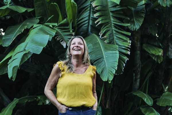 Smiling woman by leaves of palm tree