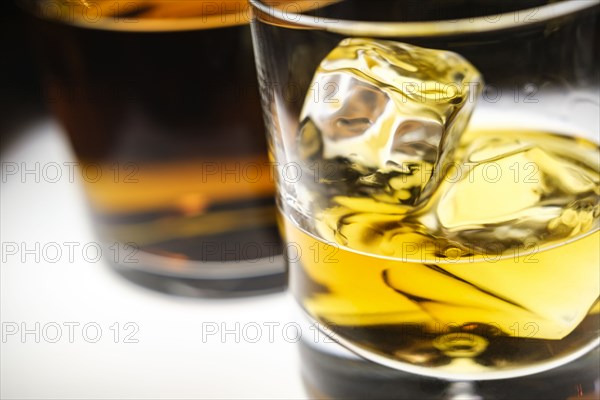 Glass of whiskey with ice cubes by bottle