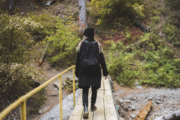young woman walking across bridge in forest
