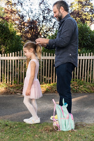 Man tying his daughter's hair in ponytail