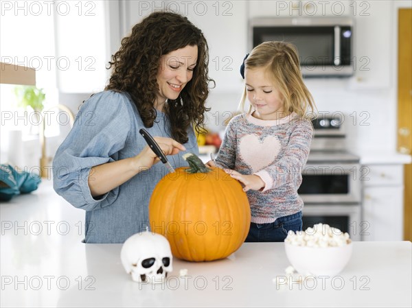 Mother and daughter carving pumpkin for Halloween