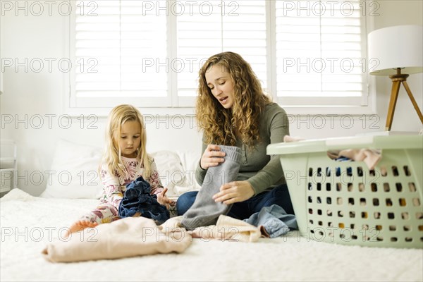 Mother and daughter folding laundry on bed