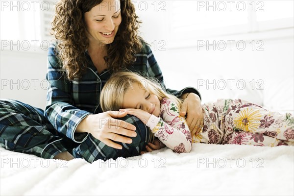 Mother and daughter hugging on bed