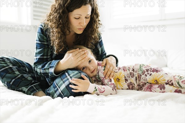 Mother and daughter hugging on bed