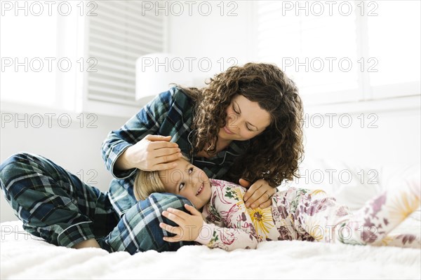 Mother and daughter hugging on bed