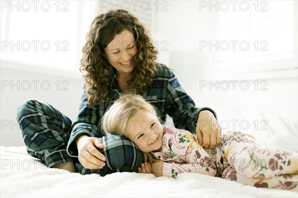 Mother and daughter hugging on bed