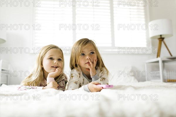 Sisters watching TV while lying on bed