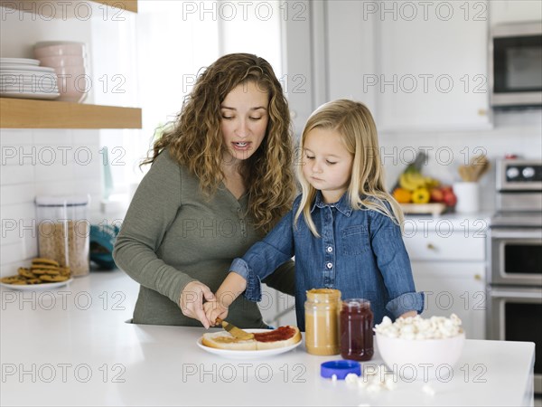 Woman making peanut butter and jelly sandwich with her daughter