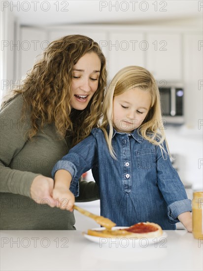 Woman making peanut butter and jelly sandwich with her daughter