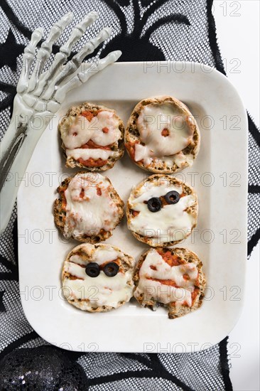 Plate of mini pizzas and hand of Halloween skeleton