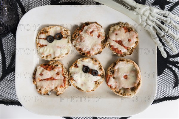 Plate of mini pizzas and hand of Halloween skeleton