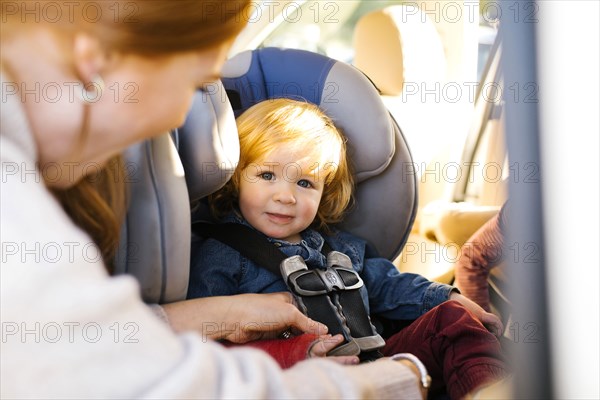 Boy having his seat belt buckled by his mother