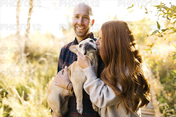 Couple with pet French bulldog in forest