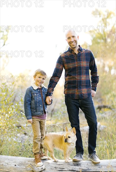 Father and son with pet French bulldog on fallen tree