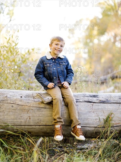 Smiling boy sitting on log