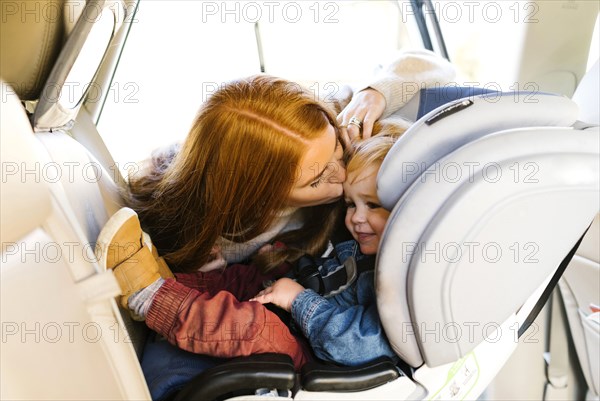 Woman kissing son in car seat