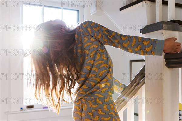 Girl in pajamas playing on banister