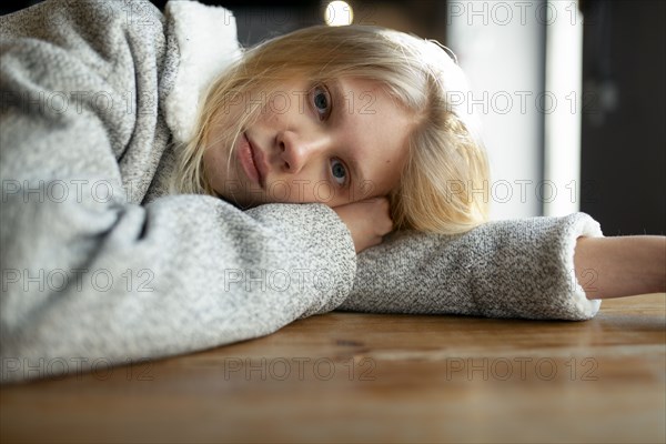 young woman in wool coat lying on cafe table