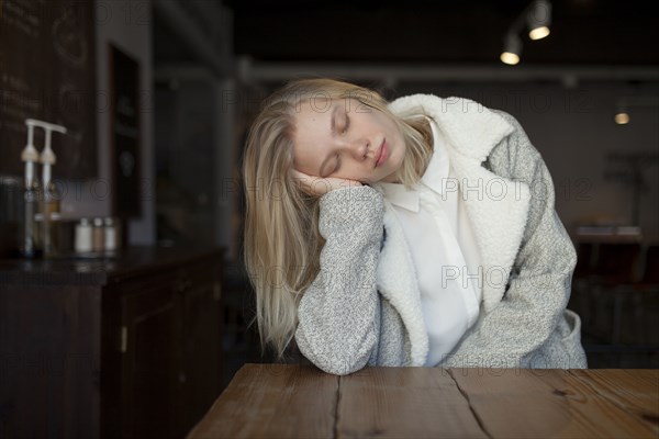 young woman sleeping at cafe table