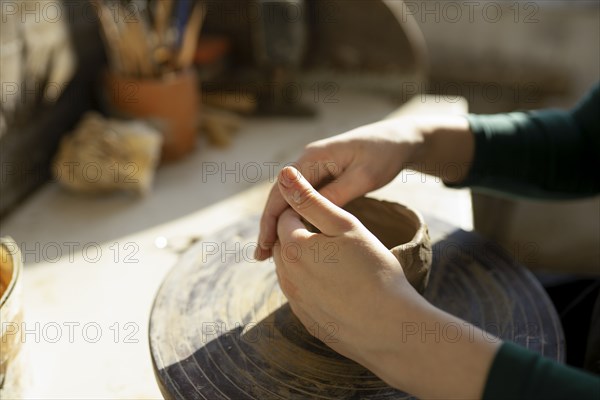 Hands of woman molding clay on potter's wheel