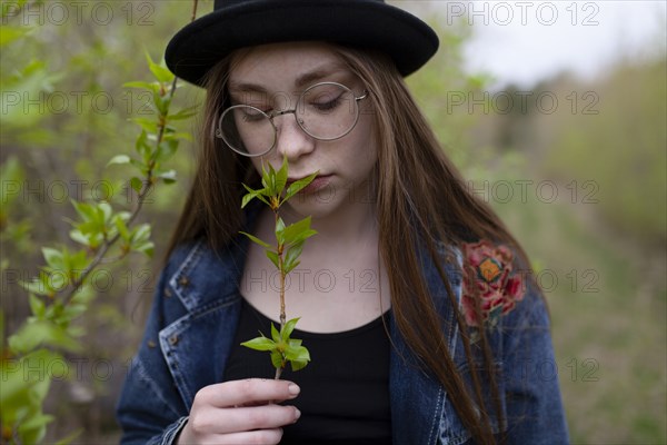 young woman smelling leaves on twig