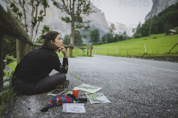 young woman painting mountains on road