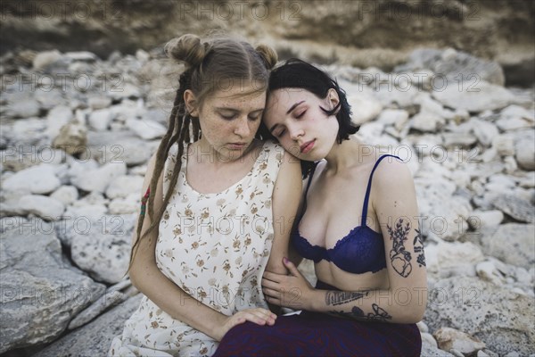 young women sitting together on beach