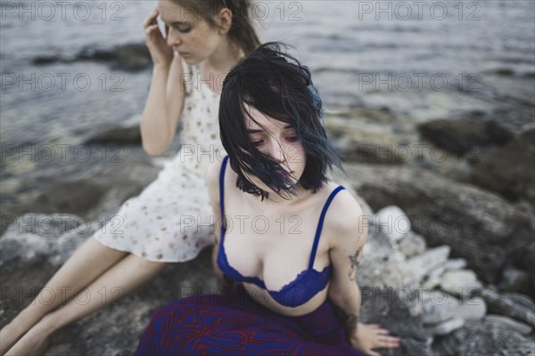 young women sitting together on beach