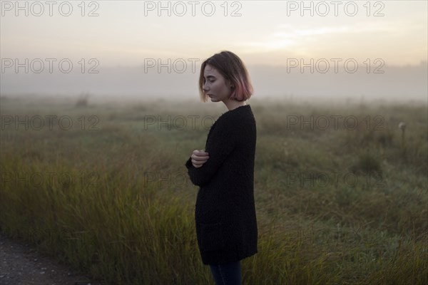 young woman in field at sunset