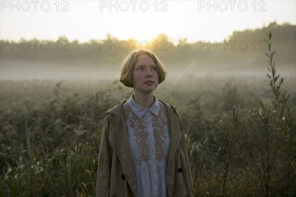 young woman in field at sunset