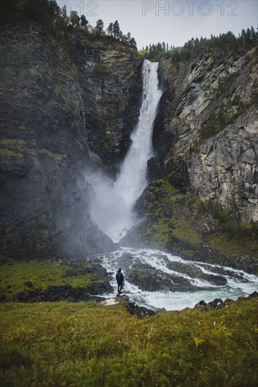 young man standing by waterfall