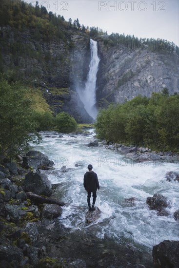 young man standing by waterfall