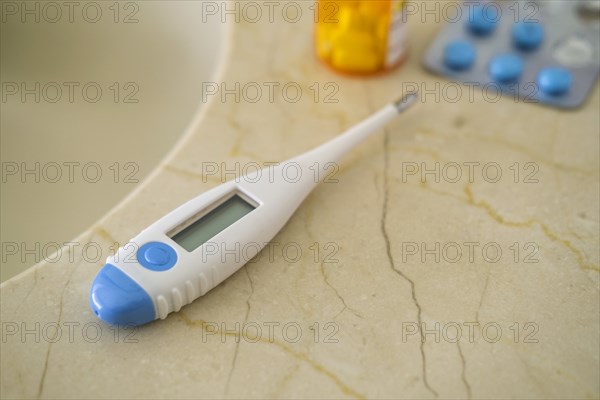 Thermometer and pills on stone surface